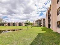 View of the surrounding area including multiple apartment buildings with grassy lawn and a small pond.