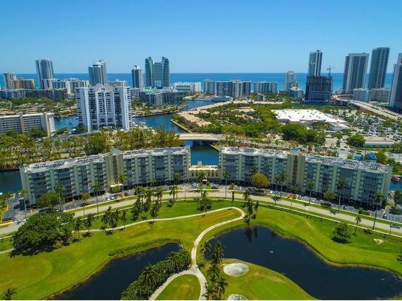 Panoramic view of high-rise buildings and waterfront area with a golf course in the foreground.