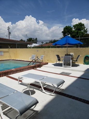 Outdoor swimming pool area with lounge chairs and an umbrella shade.