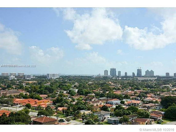Panoramic view of a cityscape with residential areas and distant high-rise buildings.