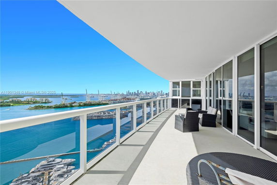 Panoramic balcony view of a coastal cityscape with high-rise buildings.