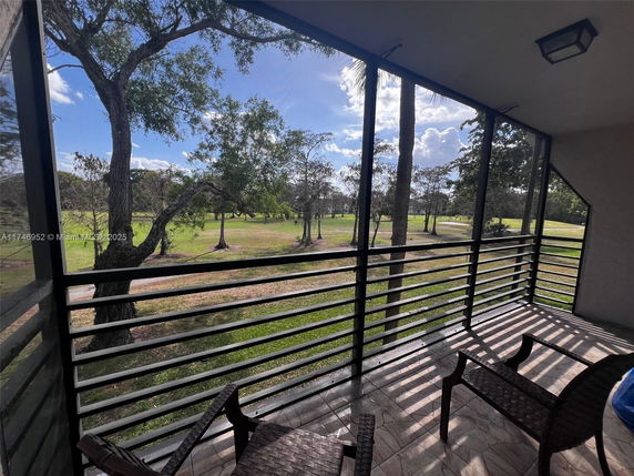 View from a balcony showing trees and open grassland.