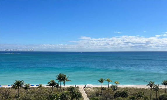 Wide angle view of the ocean and beach with clear blue water and sky.