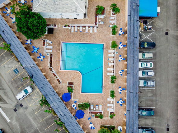 Aerial view of a rectangular swimming pool surrounded by lounge chairs and umbrellas.