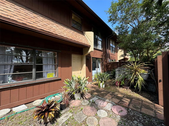 Front view of a two-story house with brown wooden exterior and multiple windows.