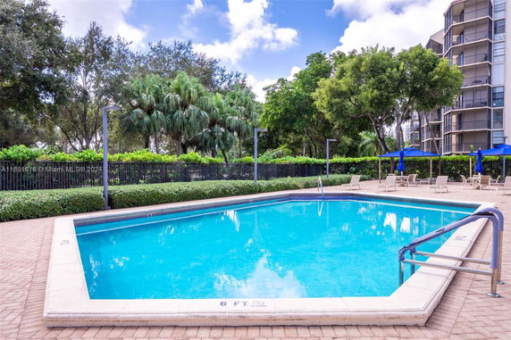 Outdoor swimming pool area with surrounding trees and adjacent building.