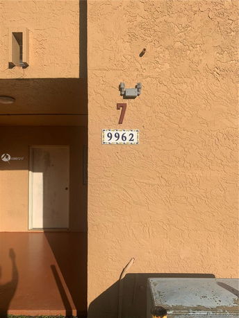 Front view of a textured wall with a door and unit number displayed.