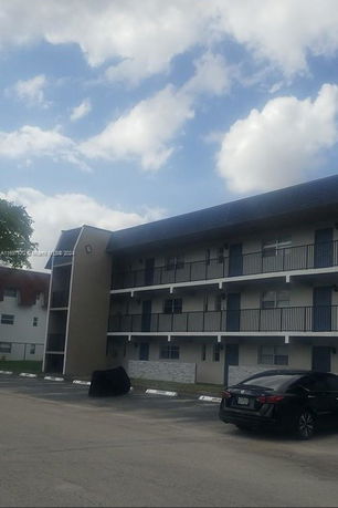 Front view of a multi-story residential building with parking area.