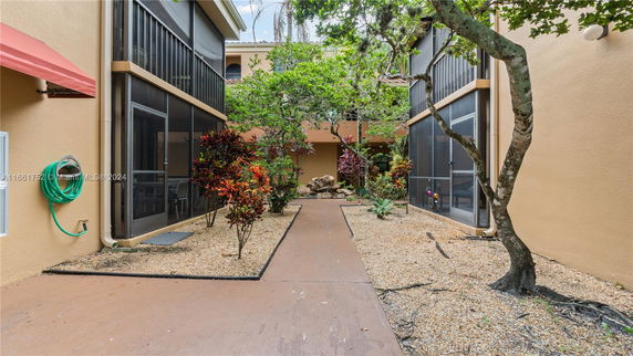 Outdoor view of a two-story building with screened porches and a central walkway with plants.