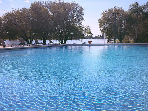 Outdoor swimming pool with lounge chairs and trees around it.