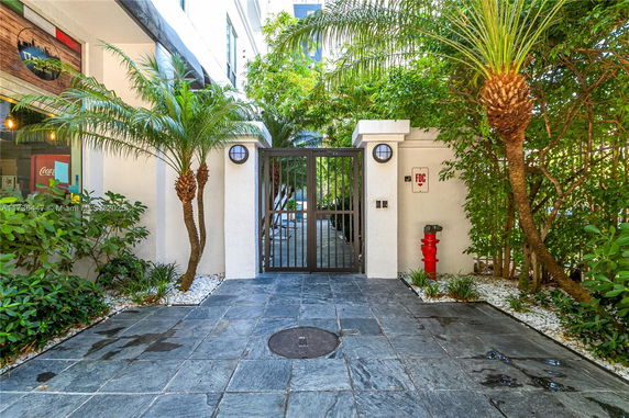 Entrance gateway with pavers and greenery on both sides.