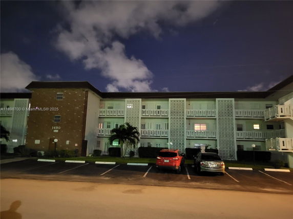 Front view of a multi-story residential building with a parking lot in front.