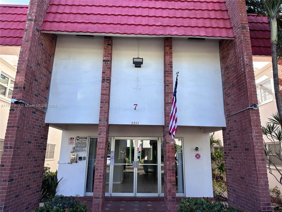 Front view of a building with red brick pillars and a red roof.