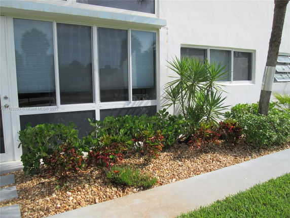 Front view of a building with large windows and landscaped garden.