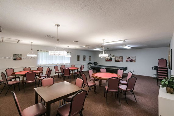 Room with several tables and chairs, decorated with hanging lights and wall art.