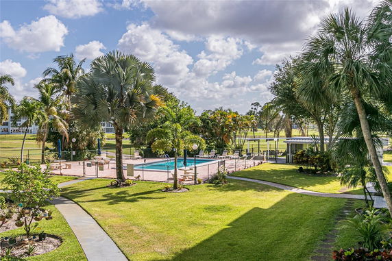 View of a landscaped area with a pool, surrounded by palm trees and greenery.