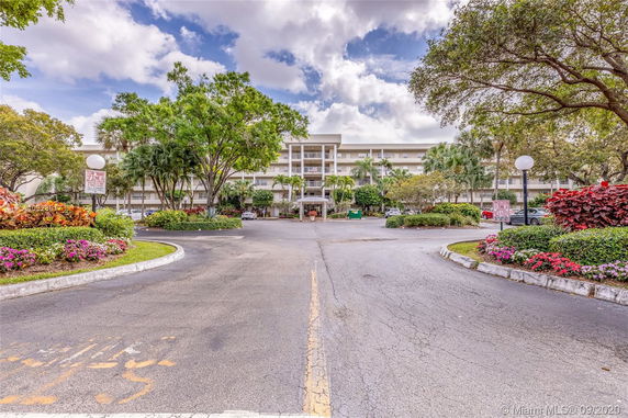 Front view of a multi-story residential building with balconies and a landscaped entrance.