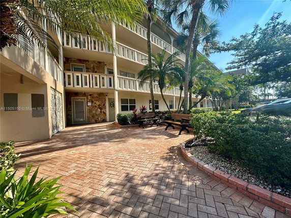 Front view of a multi-story building with balconies and landscaped entrance.