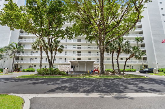 Front view of a multi-story building with balconies and greenery.