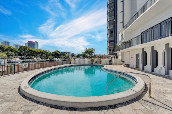 Outdoor swimming pool area next to a building with a view of the city skyline.