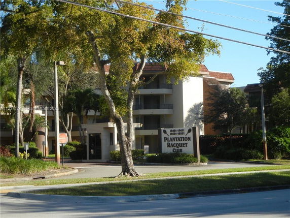 Front view of a multi-story residential building with balconies and a sign reading 'Plantation Racquet Club'.
