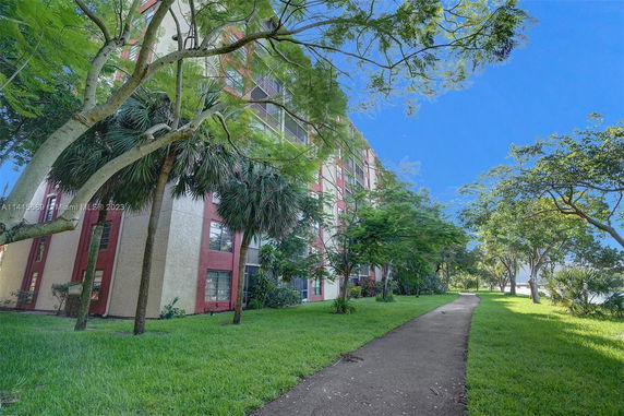 View of a multi-story building with trees and a pathway nearby.