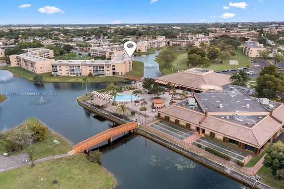 Aerial view of a residential complex with multiple buildings and a swimming pool area surrounded by water.