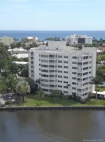 A multi-story building near a waterfront with a view of the ocean in the background.