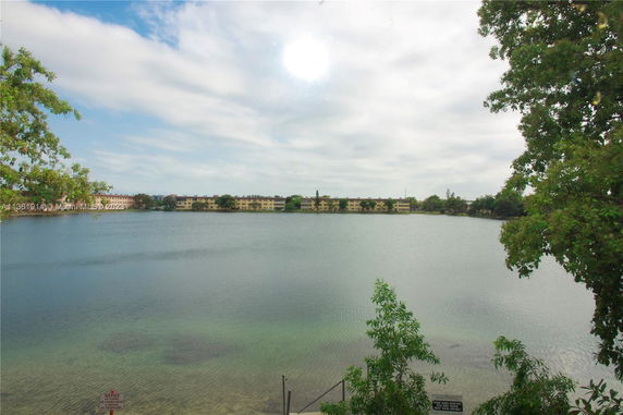 View of a lake with buildings in the distance and trees on the sides.