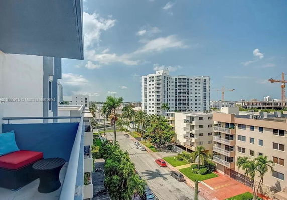 View from the balcony showing multiple apartment buildings and a street with palm trees.
