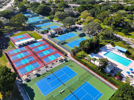 Aerial view of multiple tennis courts and a swimming pool in an outdoor recreational area.