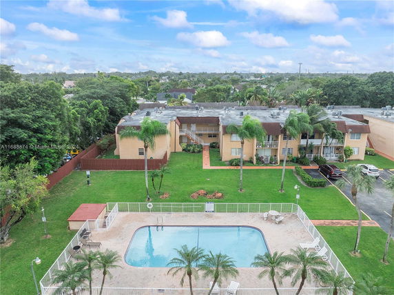 Aerial view of an apartment complex with a swimming pool and landscaped surroundings.