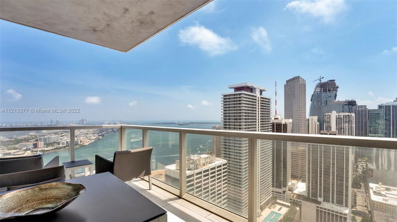 Panoramic view from a high-rise balcony overlooking city buildings and waterfront.