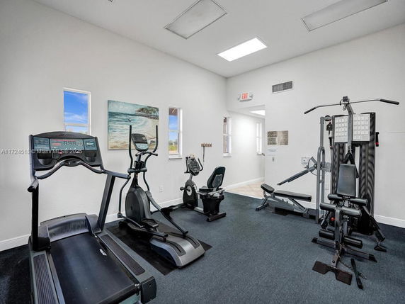 Room equipped with various exercise machines including a treadmill and elliptical.