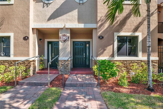 Front view of a residential building entrance with two doors and stone accents.