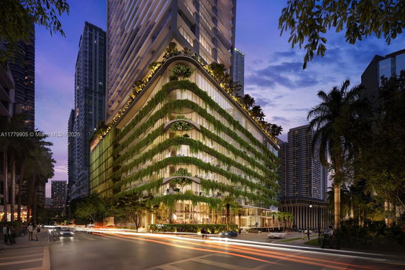 Front view of a modern multi-story building with greenery on its facade.