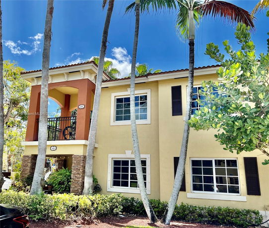 Front view of a two-story house with a balcony and archway.