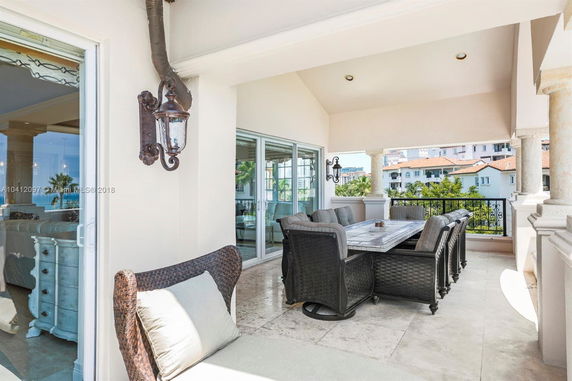 Outdoor patio with a dining table and chairs, overlooking nearby buildings.