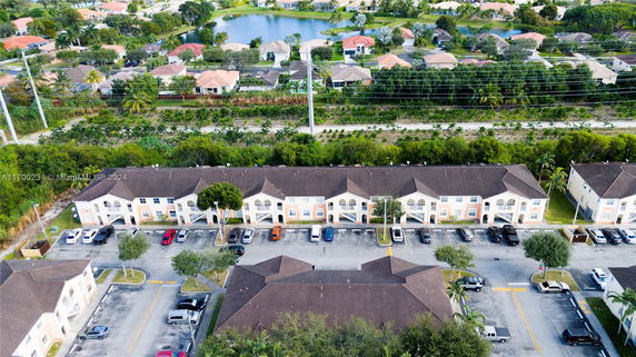 Aerial view of a residential area with multiple two-story buildings and parking spaces, surrounded by greenery.