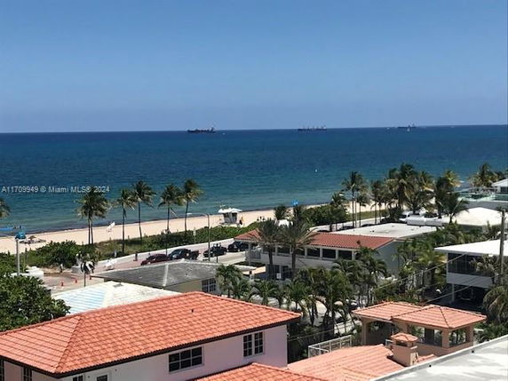 Panoramic view of beachfront buildings and ocean with palm trees.