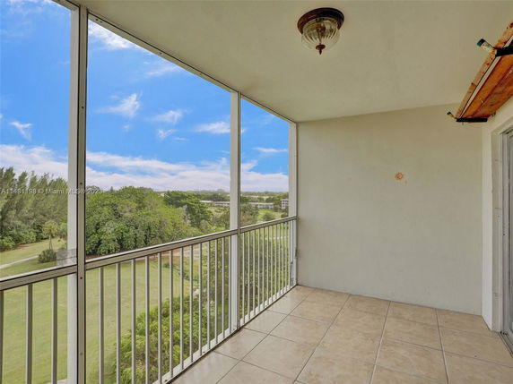 Balcony view overlooking green landscape and distant buildings.