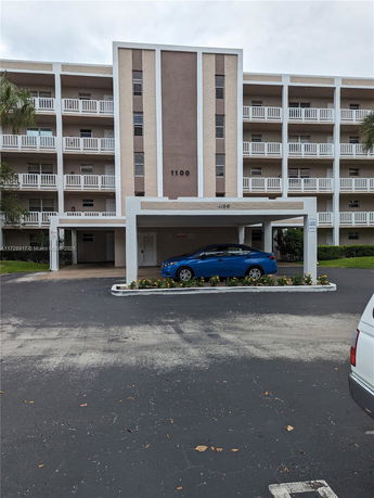 Front view of a multi-story residential building with balconies and a car parked in front.
