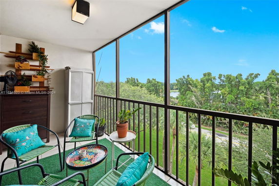 Outdoor balcony view with patio furniture and railing overlooking a lush green landscape.