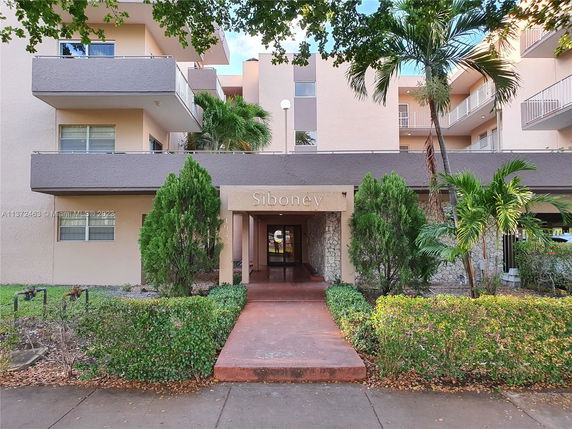 Front view of a multi-story residential building with balconies and entryway.