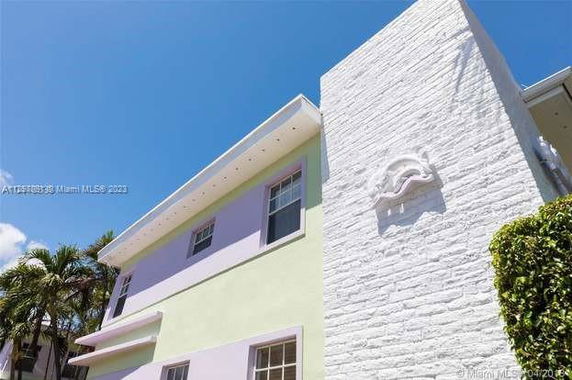 Front view of a multi-story house with pastel-colored walls and decorative wall element.