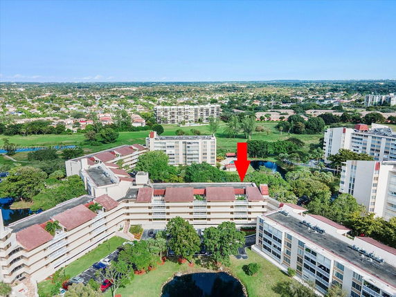 Aerial view of residential buildings surrounded by greenery and water bodies.