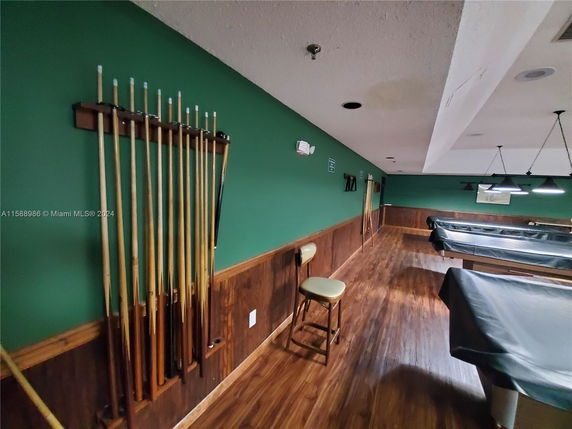 Indoor billiards room with covered pool tables and wall-mounted cue sticks.