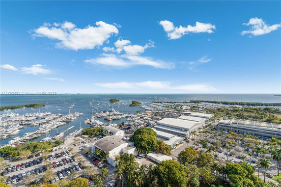 Panoramic view of a marina with boats, buildings, and parking areas by the waterfront.