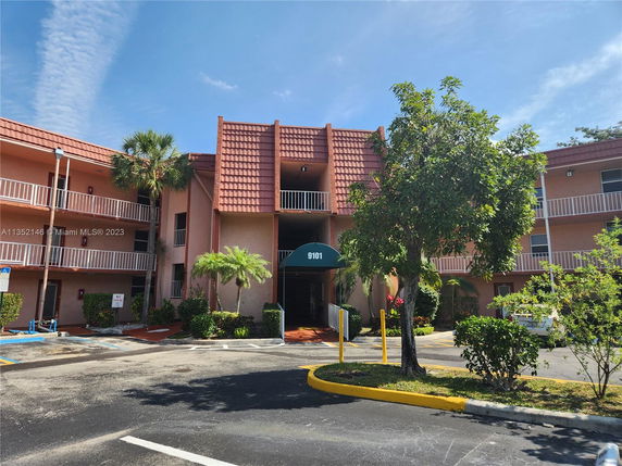 Front view of a multi-story building with balconies and a tiled roof.