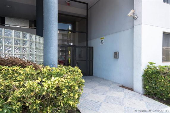 Entrance view of a building with a glass door and tiled pathway.
